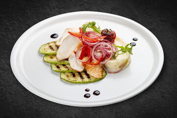 Baked chicken fillet on a pillow of mashed potatoes. Isolated on a black background.