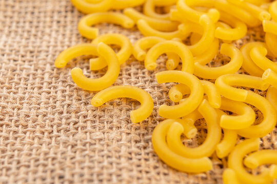 Dry yellow gobetti pasta on a rustic rough burlap. Carbohydrate wheat vegetarian food