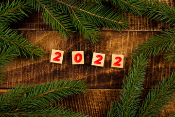 inscription 2022 fir branches on a wooden background holiday card