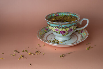 still life with a mug of tea and tea leaves scattered nearby