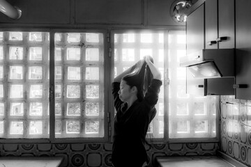 Fototapeta na wymiar Sensual chica asiática con camisa y medias baila en cocina blanco y negro