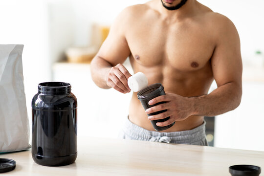 Closeup of young man with bare torso making protein shake to build up muscles ot lose weight at kitchen