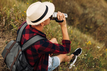 hiker sits on the top of the mountain, man with a cup of coffee sits on a rock with a view of the nature around