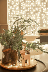 Decorated table in the Christmas interior. Christmas tree. Close-up a small house, Cones, garland, and other Christmas tree toys. light from the garlands