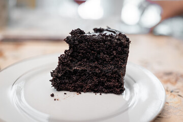 Closeup macro of dark death by chocolate layered dark cake one slice piece on white plate with...