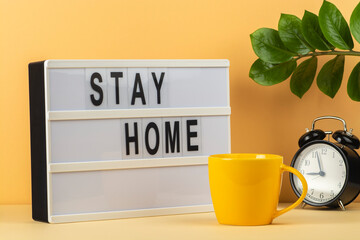 Blackboard with the words Stay Home and a cup of tea on the table.