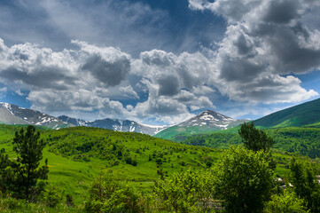 Obraz premium Spring landscape with snowy mountains and dramatic clouds 