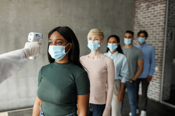 International group of people in face masks checking body temperature