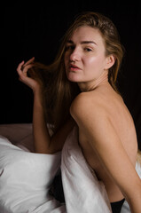 Fototapeta premium Portrait of a beautiful slender young woman with blonde hair in a white bed in beautiful aesthetic poses