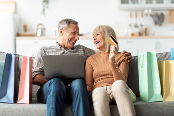 Senior Couple Shopping Online Using Laptop And Credit Card Indoor