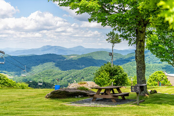 Sugar Mountain ski resort town park with idyllic picnic table bench under tree and view of ski chair slope and beautiful green North Carolina Blue Ridge Appalachia - Powered by Adobe