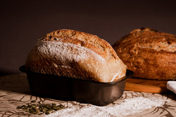 Selective Focus on a bread in a loaf pan on a table with ingredients. Blurred background. Shot with...