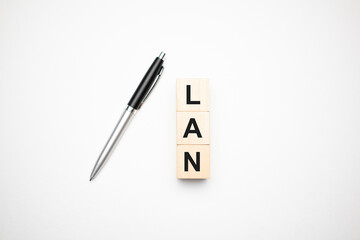 LAN is made up of wooden cubes that stand on a burgundy notebook near the pen. Business concept