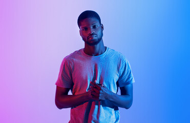 Portrait of serious black athlete in t-shirt looking at camera in neon light. Active lifestyle,...