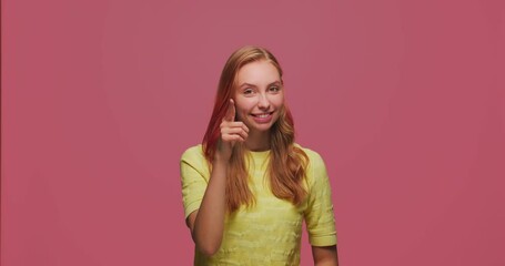 Smiling positive young girl touching temples by finger, pointing at camera, showing think about it gesture