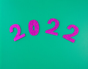 happy new year 2022 background new year holiday card on green background bright pink numbers.