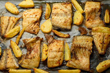 Fish dish cooked on oiled paper in the oven and potatoes on the side