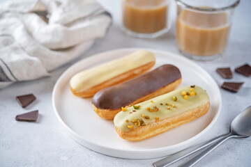 Fresh multicolored eclairs with chocolate glaze