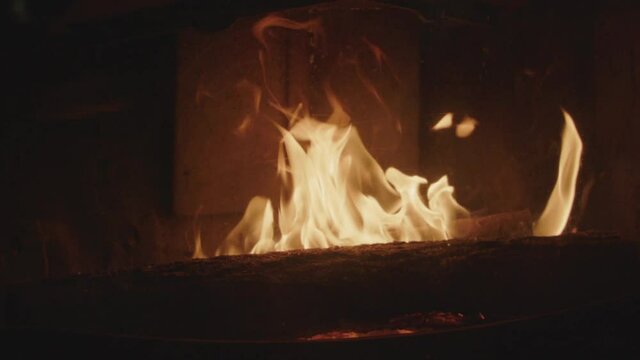 Textures of fire, embers and flames in slow motion inside a fireplace insert in a France house during winter.
