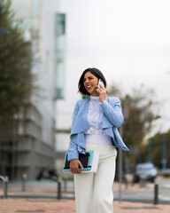Obraz premium Successful woman talking on her smartphone while walking down the street smiling