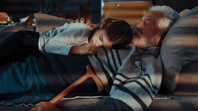 Cute little girl sleeps with her grandfather late at night
