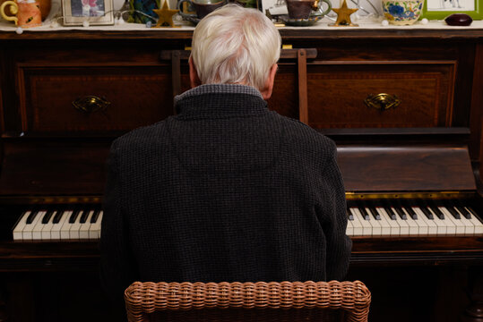 Mature man playing piano as a hobby he is facing away from the camera - Powered by Adobe