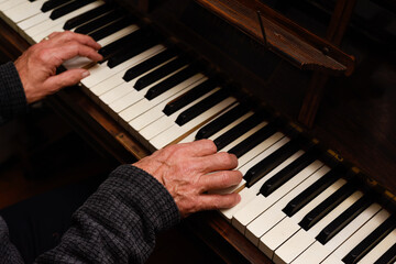 Mature male hands playing piano with focus on hands and keyboard