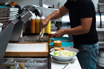 Obraz na płótnie Canvas Restaurant kitchen employee preparing customer food order