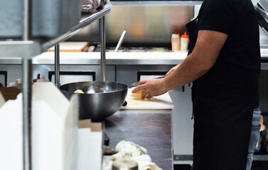 Restaurant kitchen employee cutting potatoes with knife