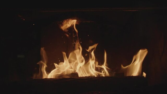 Textures of fire, embers and flames in slow motion inside a fireplace insert in a France house during winter.