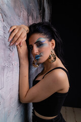 Fototapeta premium Brunette with art makeup in dark clothes in a photo studio