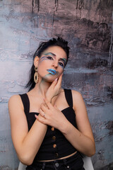 Brunette with art makeup in dark clothes in a photo studio