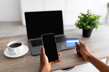 Closeup of black lady with smartphone, laptop and credit card shopping online, using new mobile app or website, mockup