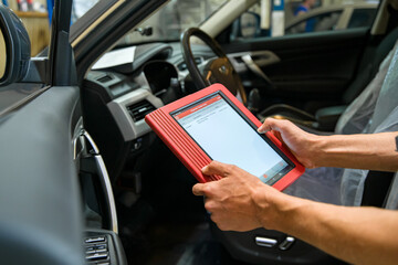 diagnostic tool in the hands of a car repair technician at a shallow depth of field