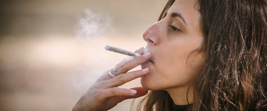 Closeup detail view of woman smoke marijuana ganja joint cigarette