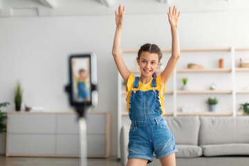 Cheerful teen girl dancing at camera filming vlog on cellphone