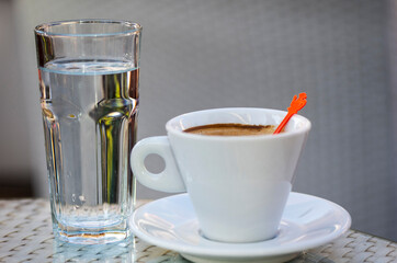 White cup of coffee with glass of water. Espresso coffee early in the morning.