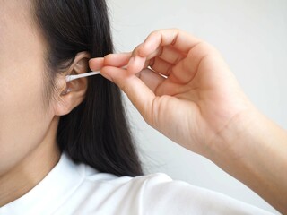 Young woman cleaning ear with cotton bud. closeup photo, blurred.