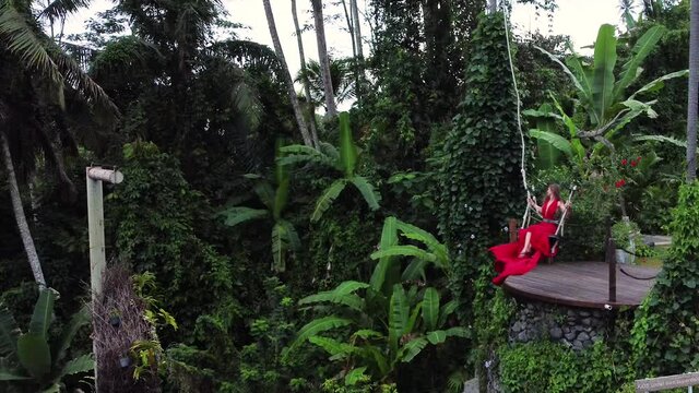 Pretty asian woman swing in long red dress in slowmotion on rice terrace in Bali Indonesia. High quality fullhd footage