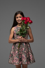 young girl looking at camera, holding red flowers., woman with flowers