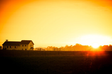 I farmhouse and field at sunrise with a slight morning mist in Indiana.