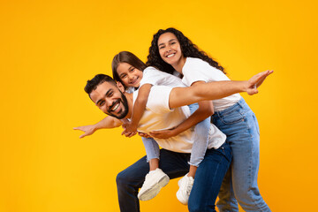 Joyful Middle-Eastern Family Posing And Having Fun Over Yellow Background