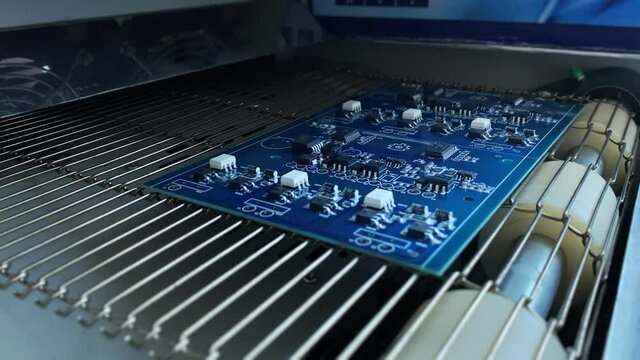 Thermal soldering of electronic elements on computer motherboards. Reflow soldering: Computer motherboard with Mounted elements exits Electronics Industrial Furnace. 