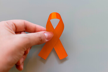 Orange december, national Skin Cancer Prevention Campaign. Hand holding orange ribbon.