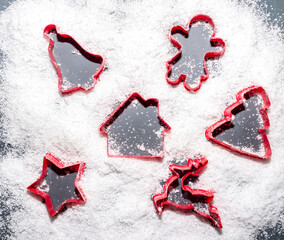 Red cake molds making silhouettes and signs in snow. Christmas and new Year idea. Flat lay, top view. Minimal abstract winter holidays concept. Copy space.