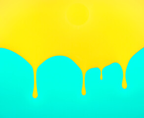 Dripping yellow paint on turquoise blue background. Flat lay, top view. Minimal abstract summer, fashion or makeup concept. With copy space.