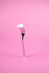 Fork with snowballs on pastel pink background. Christmas and New Year idea. Minimal abstract winter holidays concept. 
