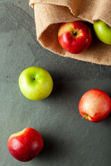 apples of different varieties are seen on dark stone and wooden background. There are green tart apples and red sweet apples seen side by side. Concept image for eating apples and its benefits.