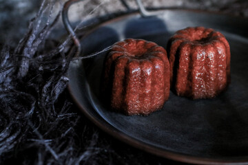 Caneles de bordeaux on dark background with sunrise. French pastry Canele rum and vanilla flavor thick caramelized crust