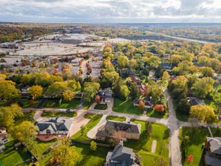 Aerial view of residential neighborhood in Northfield, IL. Lots of trees starting to turn autumn colors. Large residential homes, some with solar panels. Meandering streets